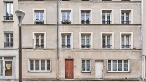 A multi-story building with a uniform facade, multiple windows, and balconies with potted plants. - Studio Tempa, proche du Château de Vincennes - Welkeys (Vincennes)