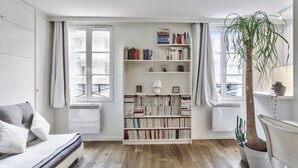 A modern living room with a bookshelf, a sofa, a coffee table, and a potted plant. - Studio Tempa, proche du Château de Vincennes - Welkeys (Vincennes)