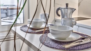 A kitchen counter with a coffee maker, two bowls, and a set of cutlery on a woven placemat. - Studio Tempa, proche du Château de Vincennes - Welkeys (Vincennes)
