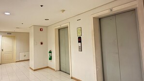 Un pasillo con piso de baldosas, un ascensor y una puerta con el símbolo del número.