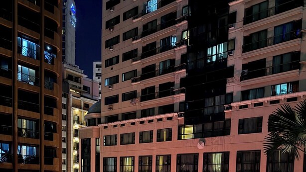 Un edificio de varios pisos con un atrio central, ventanas amplias y una escalera que conduce a los pisos superiores.