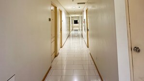 Un largo y estrecho pasillo de hotel con paredes blancas y puertas a ambos lados.