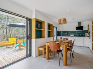 A modern kitchen with a dining area, wooden furniture, and a view of the outdoors.