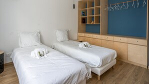 Hotellihuone, jossa on kaksi erillistä sänkyä, puinen vaatekaappi ja sininen tehosteseinä.