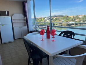 A dining area with a table, chairs, and a view of a river and buildings.