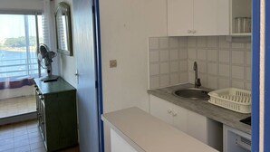 A compact kitchen with a sink, a window with a view, and a radiator. - 2 Room apartment with pool Richelieu beach Cap d'Agde (LE CAP D AGDE)