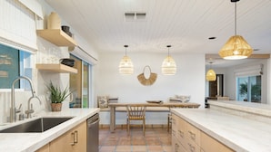 Una cocina moderna con una isla central, luces colgantes y vistas al exterior.