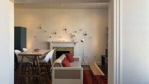 A living room with a fireplace, a dining table with chairs, a sofa with cushions, and a bookshelf. - The Bakery Loft in Blairsville (Blairsville)