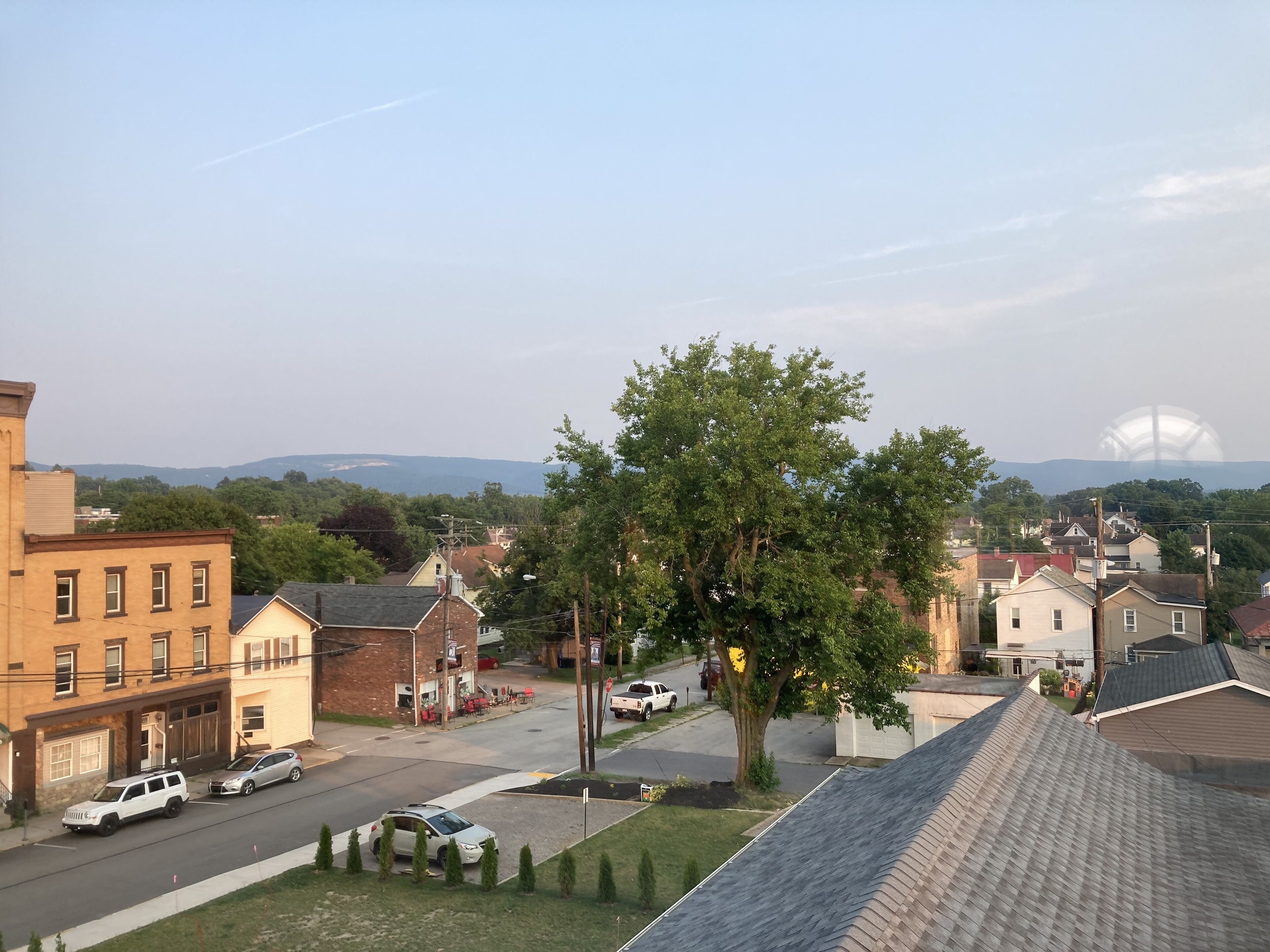 A residential street with houses, a tree, and a clear sky.