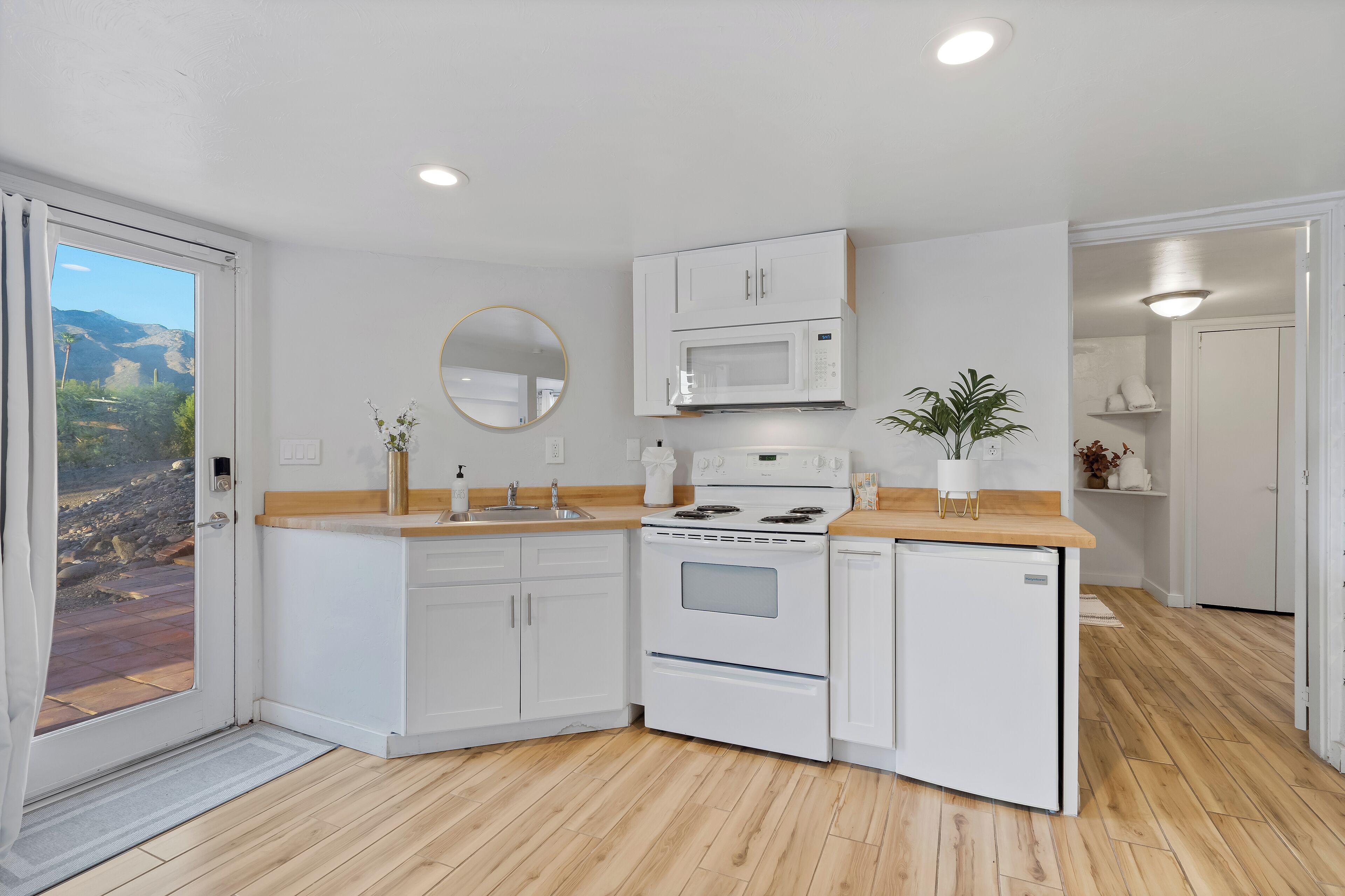 Una cocina moderna con gabinetes blancos, microondas, estufa y fregadero.