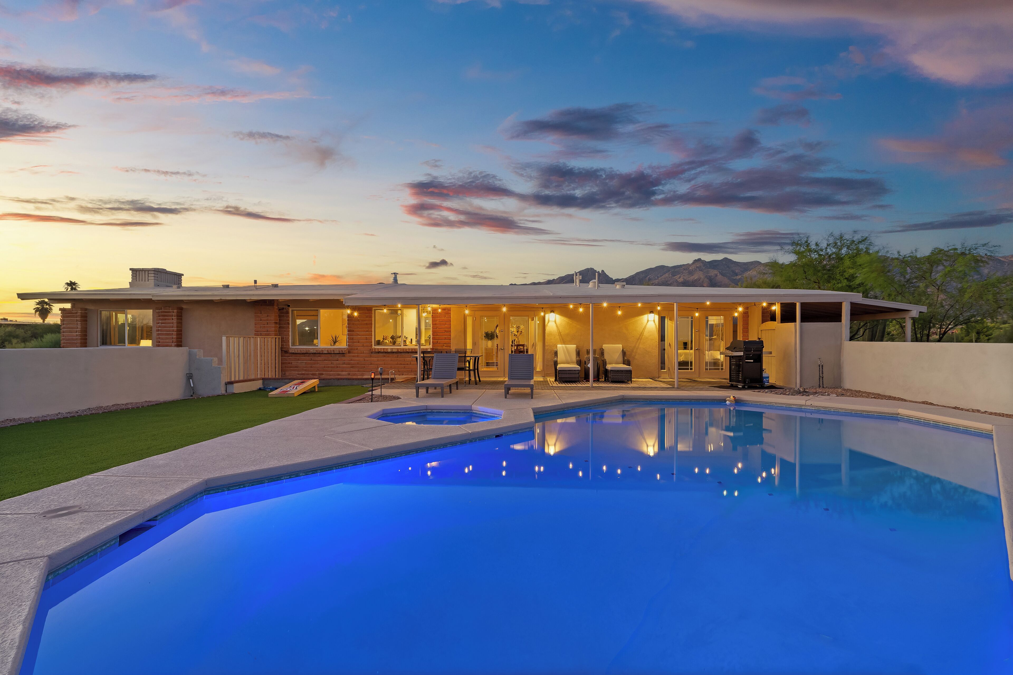 A modern house with a swimming pool, outdoor seating, and a mountain backdrop.