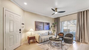 Un salon comprenant un canapé, un fauteuil, une table basse, une lampe et une œuvre d’art accrochée au mur.