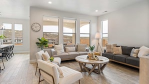 A spacious living room with a sofa, armchairs, and a coffee table. There are large windows offering a view of the desert landscape. - Zion's Gateway Retreat by RedAwning (Washington)