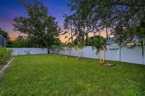 A backyard with a white fence, green grass, and trees. - Family Getaway• Free Heated Pool• Nintendo• Hummocks • Shuffleboard •Near Beach🌴 (North Port)