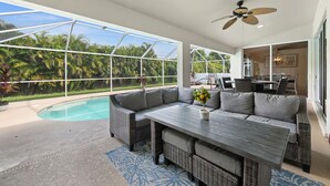 Un patio amplio con piscina, mobiliario exterior y vistas a exuberante vegetación.
