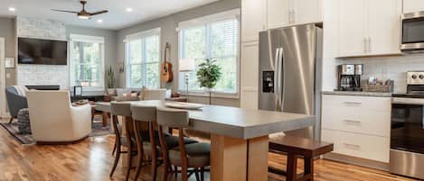 A modern kitchen with a central island, stainless steel appliances, and a dining area with bar stools.