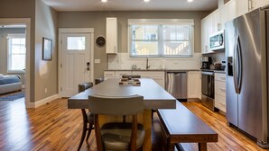 Een moderne keuken met een centraal eiland, roestvrijstalen apparatuur en een groot raam.