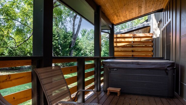 Een houten terras met een jacuzzi, een stoel en een tafeltje.
