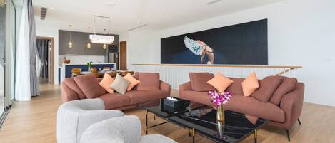 Een moderne woonkamer met twee banken, een salontafel en een eethoek op de achtergrond.