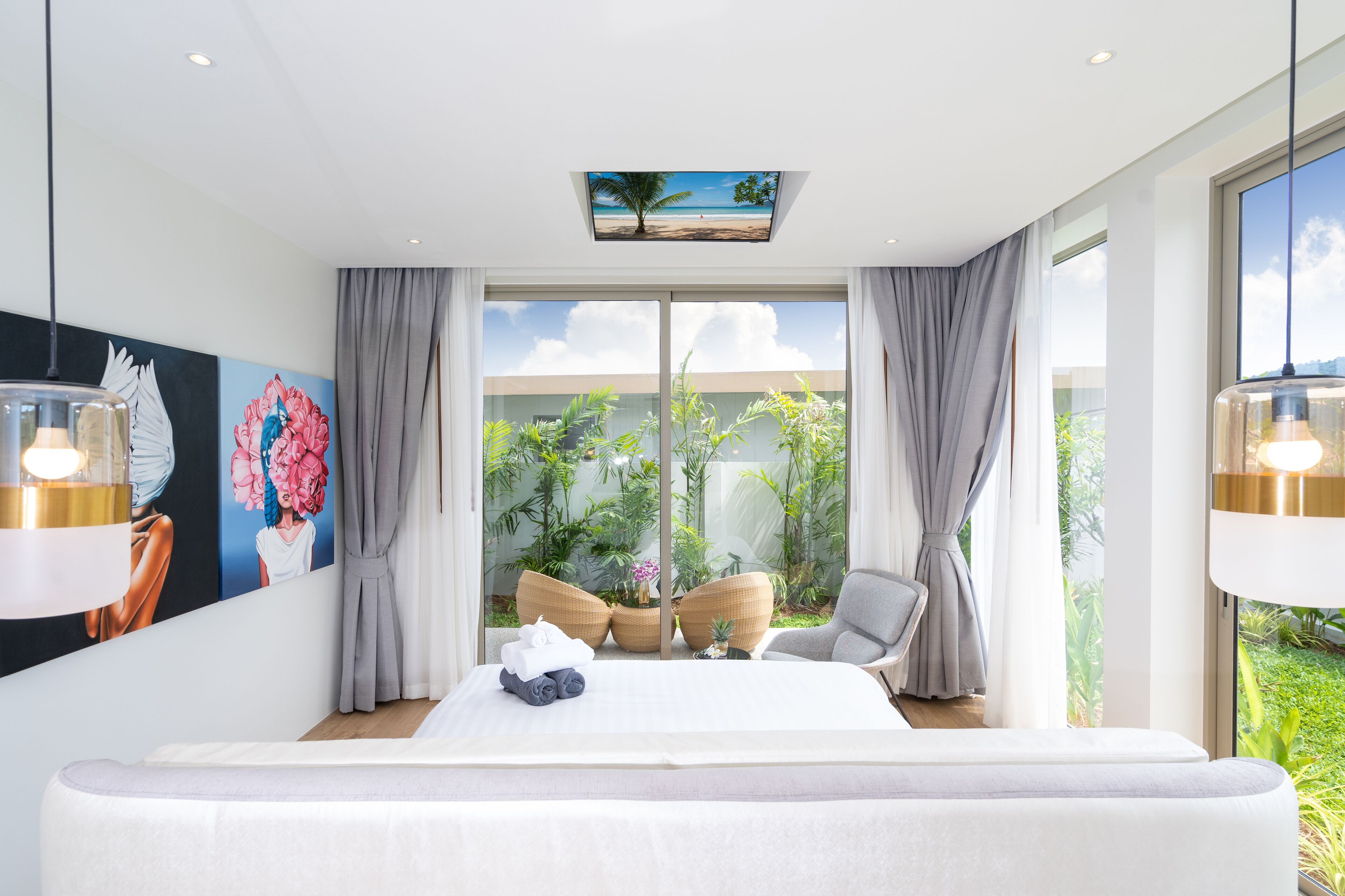 A modern bedroom with a large bed, a view of the outdoors, and a ceiling artwork.