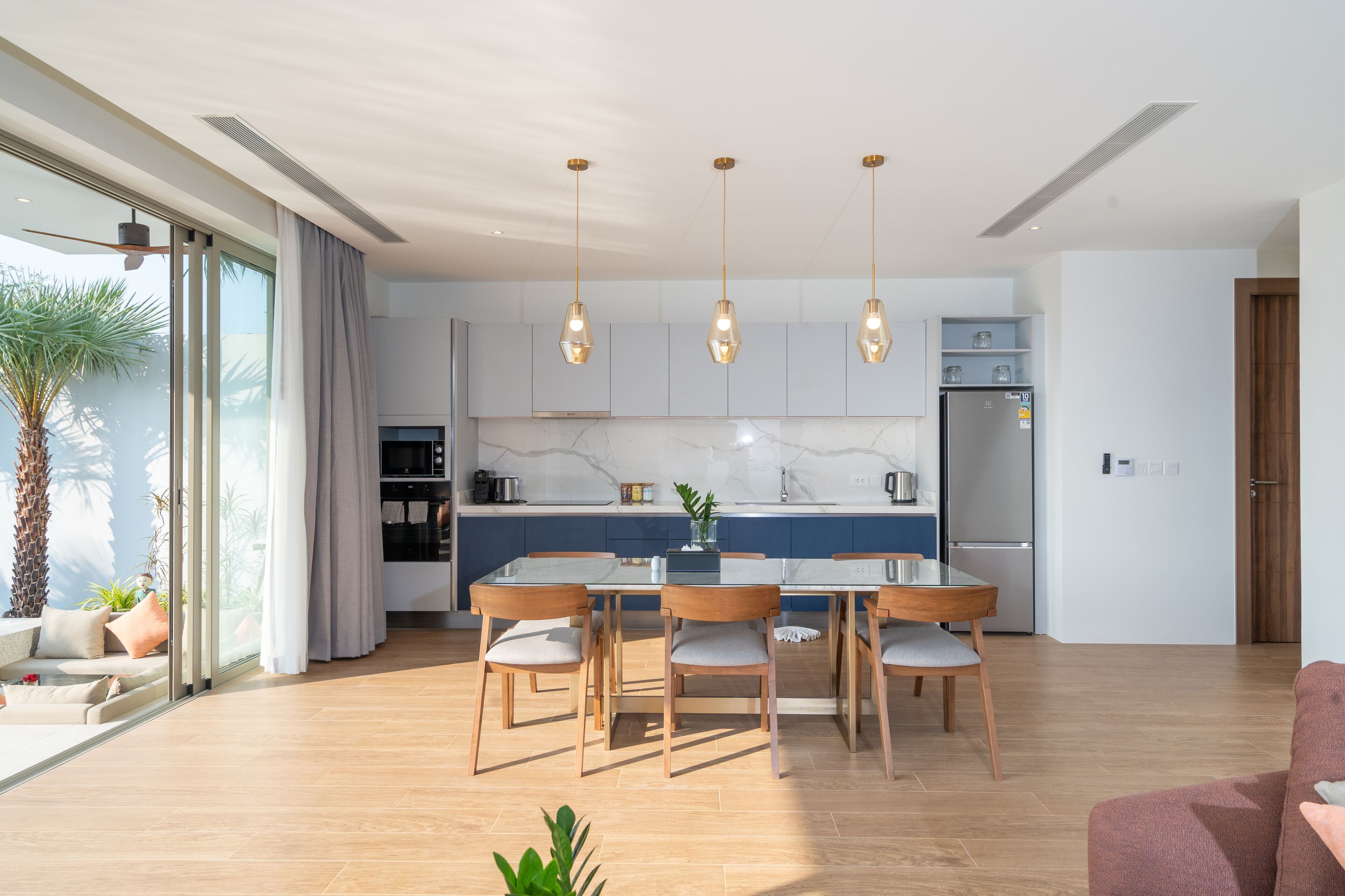Une cuisine moderne dotée d’un îlot central, de luminaires suspendus et d’un coin repas avec des chaises et une table.