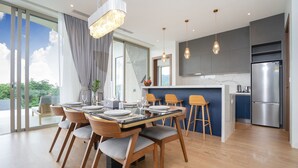 Una cocina moderna con un refrigerador de acero inoxidable, sillas de madera y una mesa de comedor para seis personas.