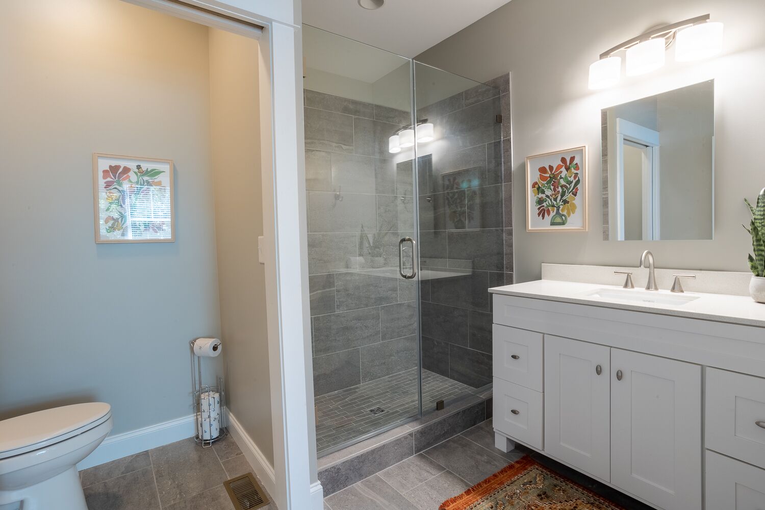 A modern bathroom with a glass-enclosed shower, a white vanity with a mirror, and a toilet.