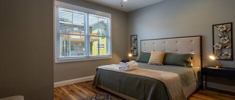 A bedroom with a bed, a nightstand, a ceiling fan, and a window with blinds.