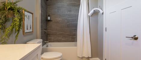 A bathroom with a bathtub, toilet, and a shower curtain.