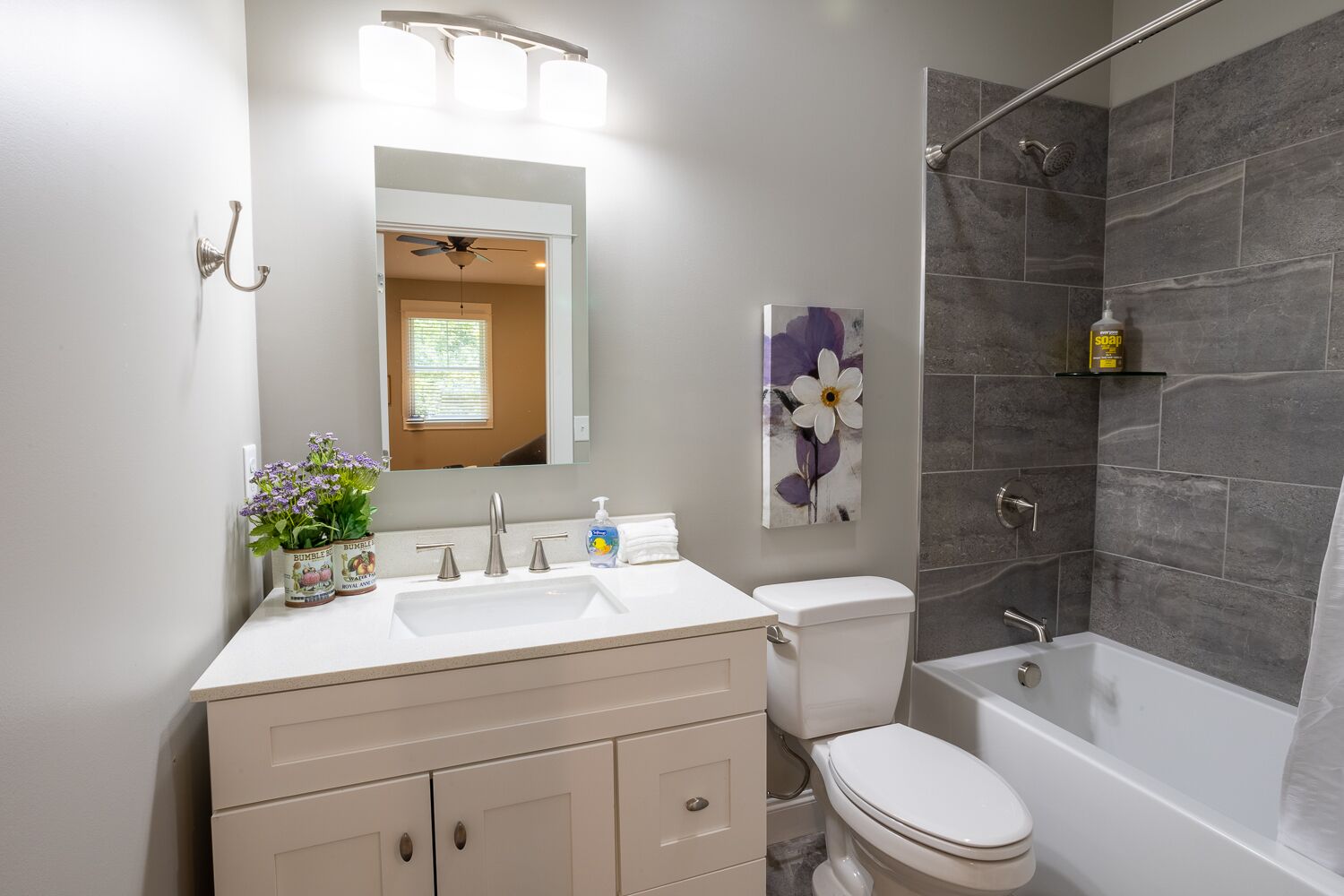 Un baño moderno con lavamanos, tocador, inodoro y bañera blancos.