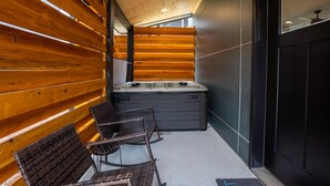Ein moderner Wellnessbereich mit Holzlamellen, einer Whirlwanne und Korbstühlen.