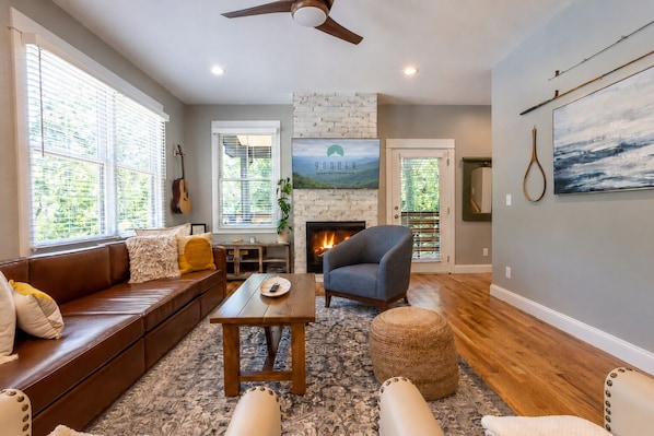 A living room with a fireplace, a sofa, a coffee table, and a ceiling fan.
