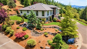A two-story house with a landscaped garden featuring a pond, various shrubs, and a well-maintained lawn. - New Listing - Breathtaking vacation/work remotely in wine country! (Forest Grove)