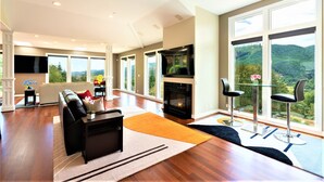 A spacious living room with a fireplace, a sofa, and a dining area with bar stools. - New Listing - Breathtaking vacation/work remotely in wine country! (Forest Grove)