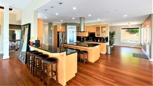 A modern kitchen with a central island, bar stools, and wooden flooring. - New Listing - Breathtaking vacation/work remotely in wine country! (Forest Grove)