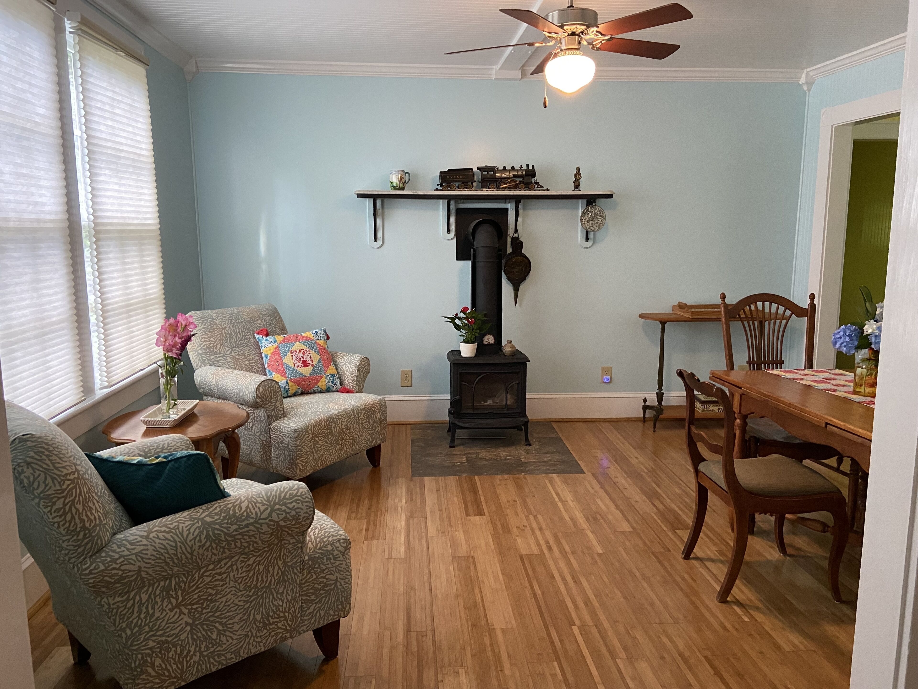 Una sala de estar con muebles estampados, una chimenea y un comedor con sillas de madera y una mesa.