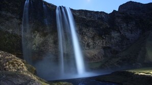 A waterfall cascading into a pool surrounded by rocky cliffs.