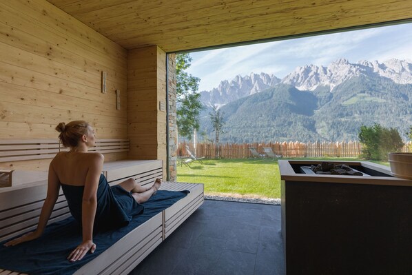 Una cabaña de madera con zona de sauna, vistas a las montañas y una chimenea.