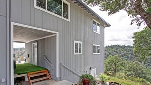 Ein graues Holzhaus mit einem grünen Rasen, einer hölzernen Bank und Topfpflanzen.