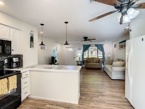 Una cucina moderna con un'isola centrale, un'area pranzo con divano e una ventola a soffitto.