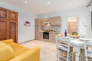 Una cocina moderna con armarios de madera, un comedor con mobiliario blanco y un sofá amarillo.