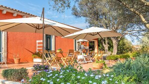 A patio with outdoor seating, a red building, and a garden with flowers. - Domos Pintadas Apt. 1 Porto Rotondo, Rudalza, Italy (Rudalza)