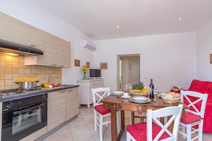Cozinha moderna com área de jantar, com fogão, forno e mesa de jantar posta para quatro pessoas.