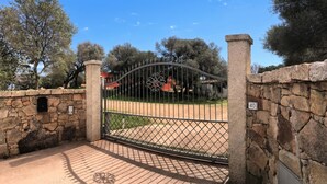A gated entrance with a stone wall, a metal gate, and a number sign indicating the location.