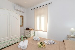 Une chambre à coucher avec un lit, une commode, un miroir et une fenêtre avec des rideaux.