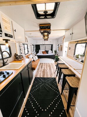 A compact RV kitchen with a central island, a stove, and a sink. - Cute Renovated RV Near Zion & St. George (Leeds)