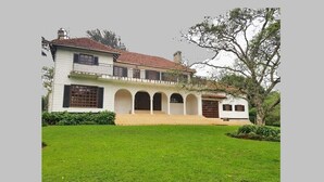 A two-story building with a white facade, a red-tiled roof, and a central courtyard with arches. - TIGONI GEM GARDENS (Limuru)