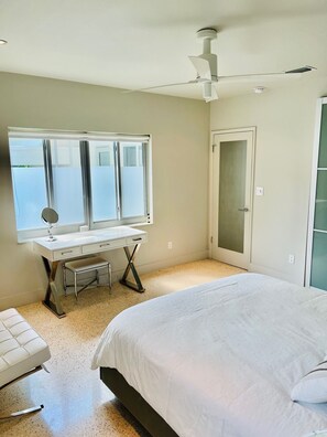Relax in this serene bedroom with a large bed, a desk, and a mirror.