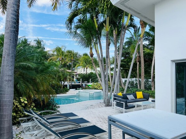 Relax by the serene pool surrounded by lush greenery and palm trees.