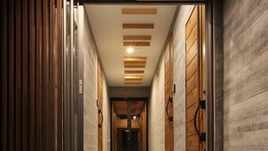 A hallway with a wooden slat door, a large ceramic bowl, and a staircase leading to a dark room. - Orchid Furano (Furano)